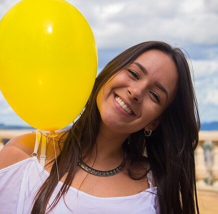 chica sonriendo con un globo amarillo