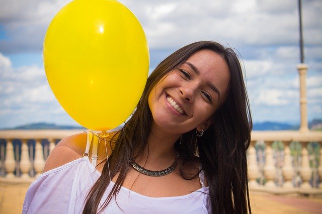 chica sonriendo con un globo amarillo