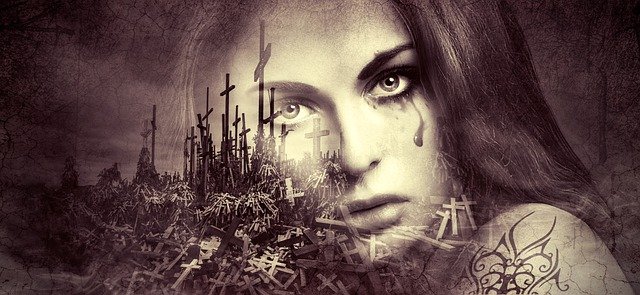 mujer llorando frente a un sitio lleno de cruces