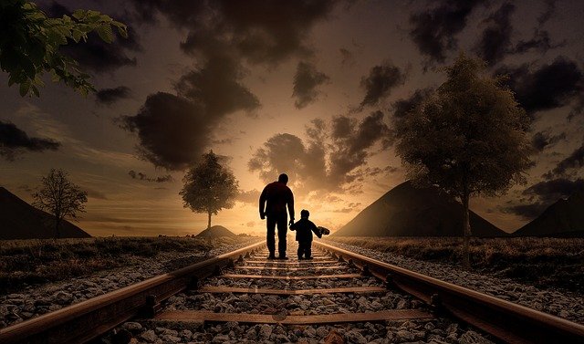padre e hijo caminando por unas vías de tren